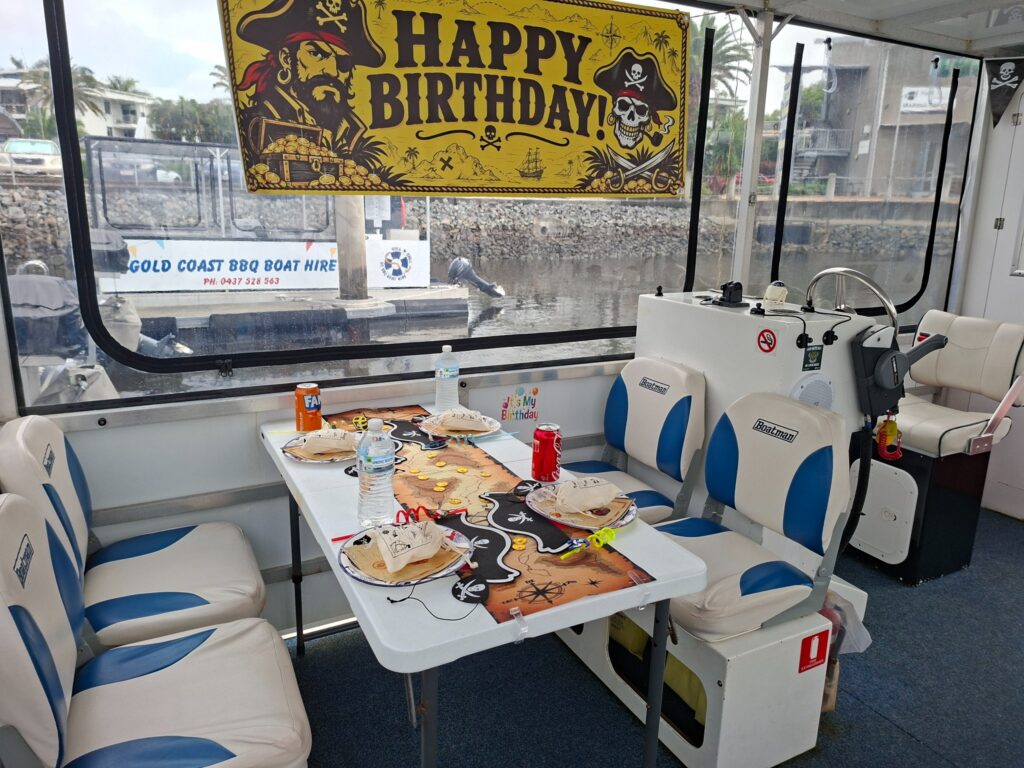 Pirate birthday party table with treasure bags, hats and birthday banner aboard a Gold Coast BBQ boat