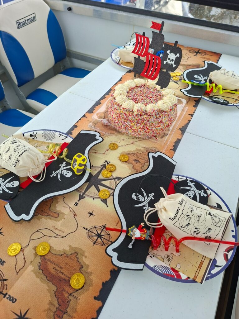 Birthday cake with pirate ship topper on a treasure-map party table