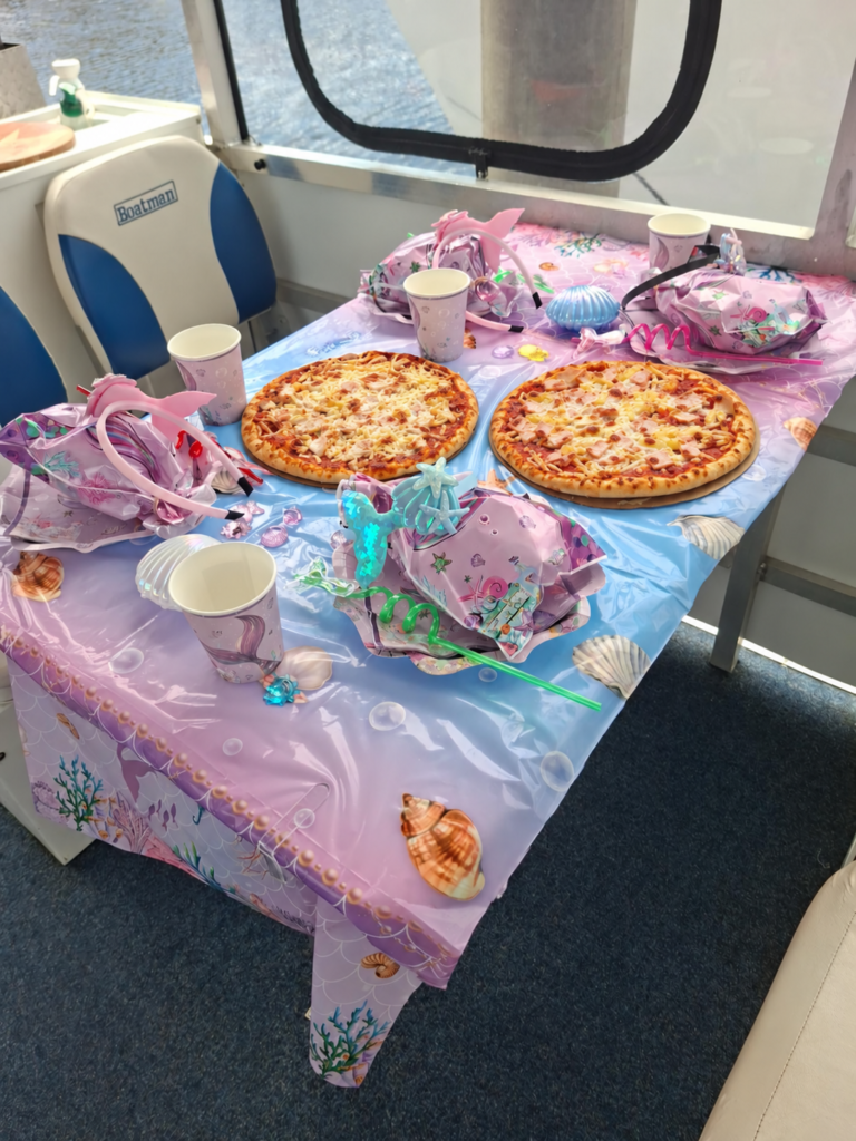 Pizzas on a mermaid-themed birthday party table aboard a BBQ boat